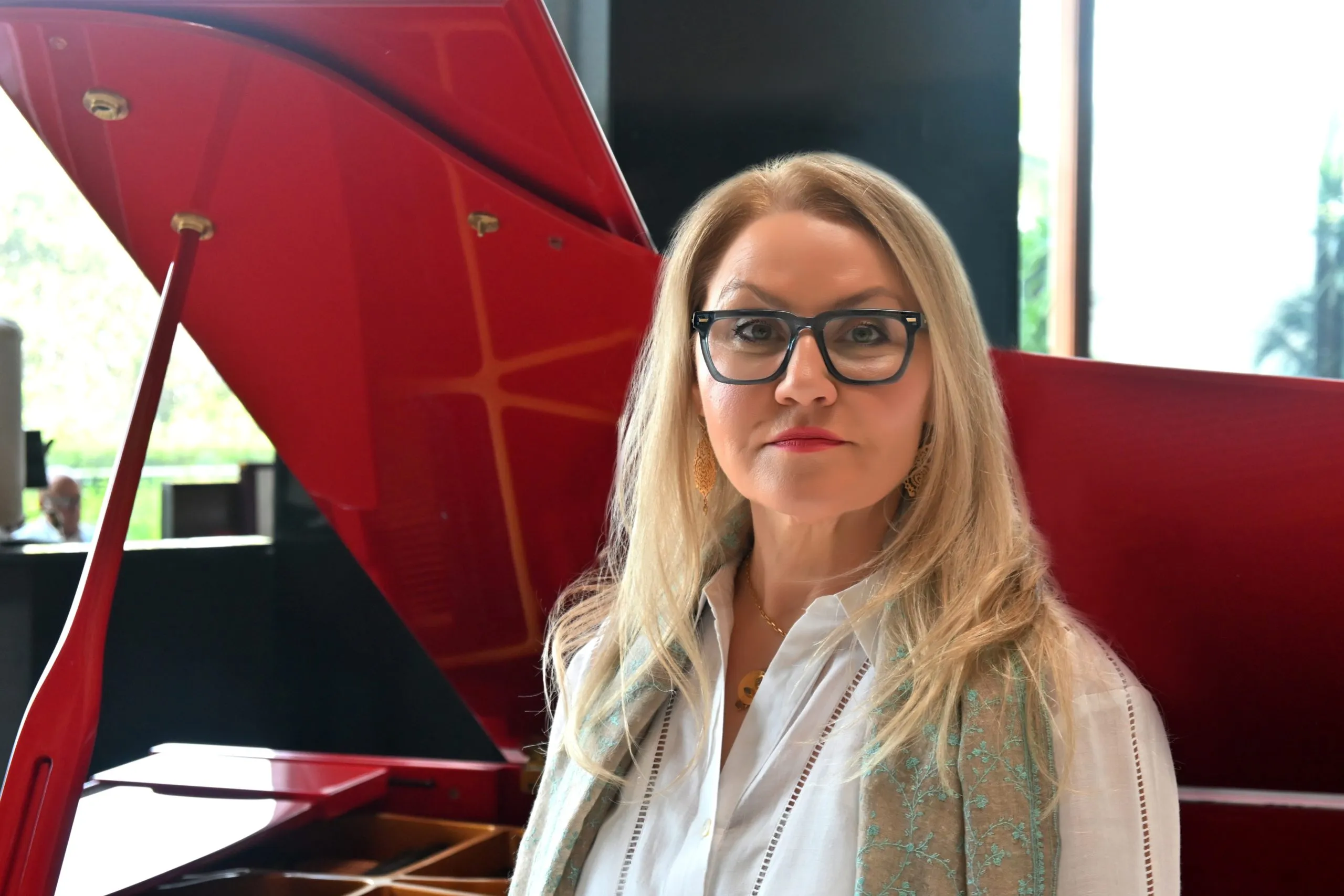 Linda Carter, fertility coach, beside a red grand piano in London